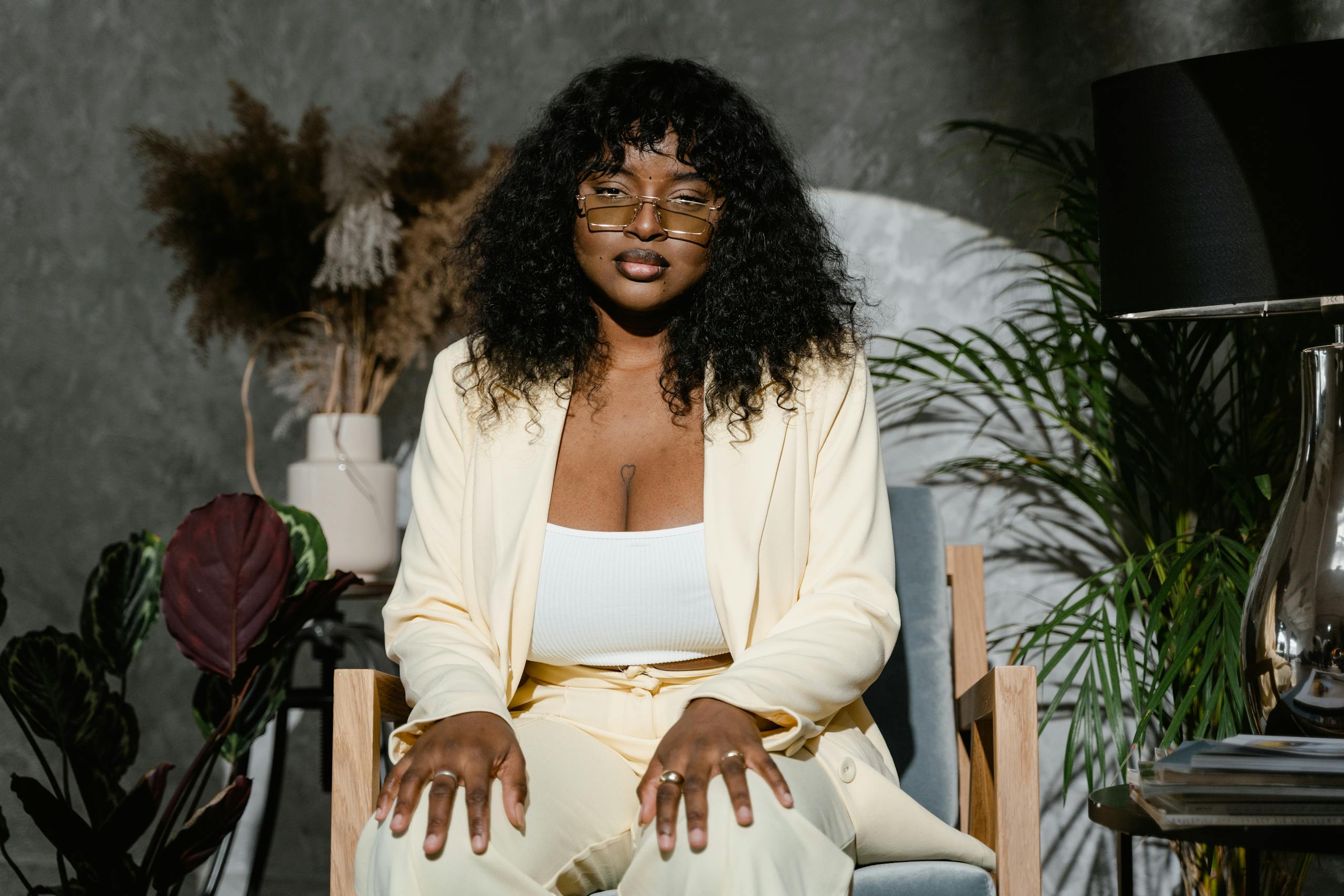 Portrait of a confident plus size woman seated indoors, conveying self-esteem and individuality.