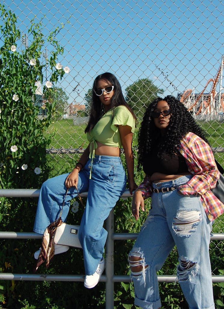 Two young women posing stylishly outdoors in casual outfits with sunglasses.