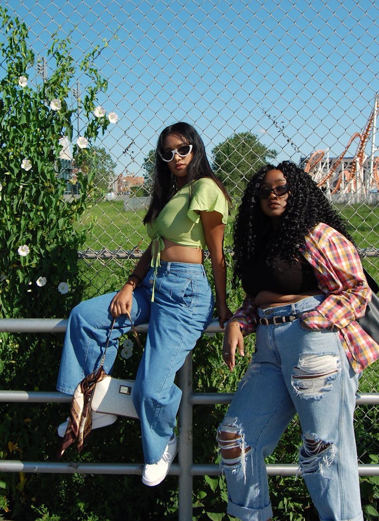 Two young women posing stylishly outdoors in casual outfits with sunglasses.