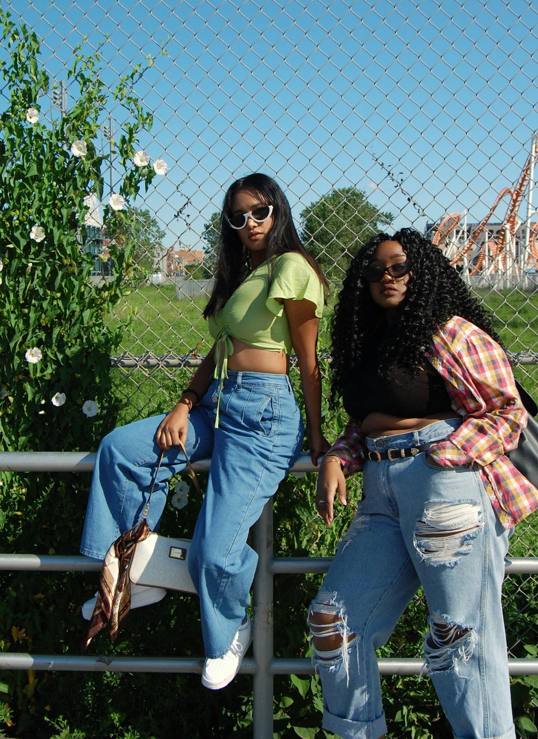 Two young women posing stylishly outdoors in casual outfits with sunglasses.